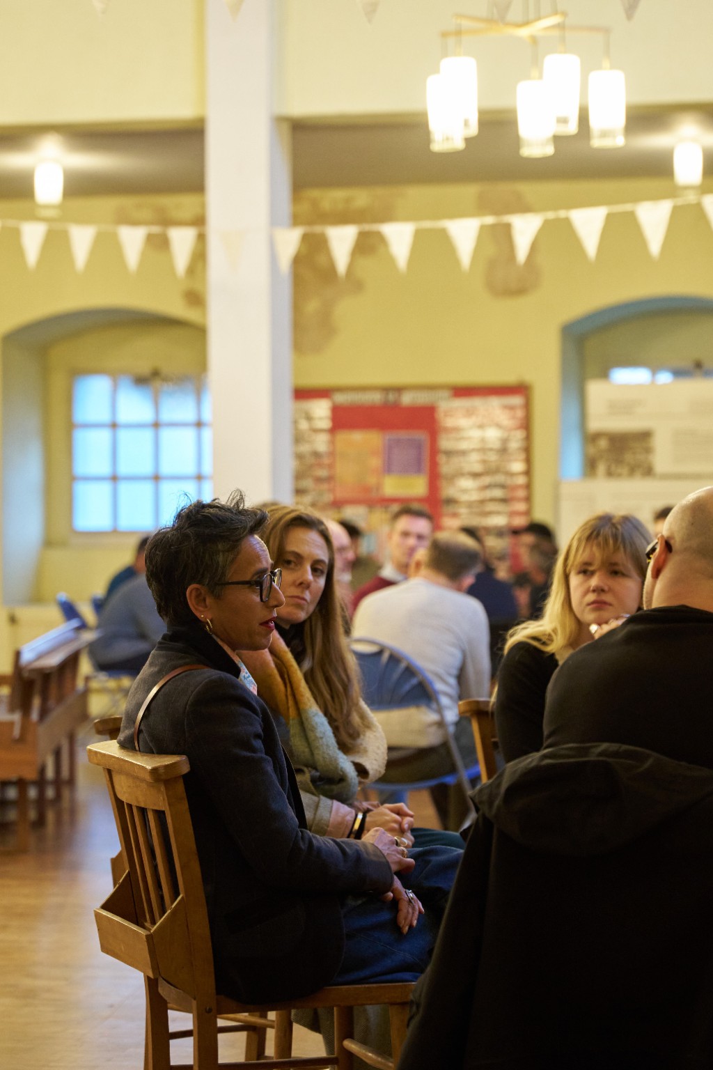 A woman in glasses taking part in a small-group conversation at Agora