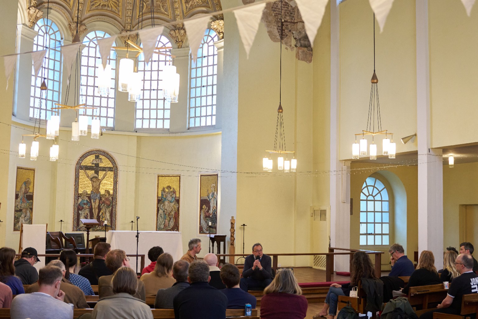 An Agora speaker and audience gathered in a bright historic venue
